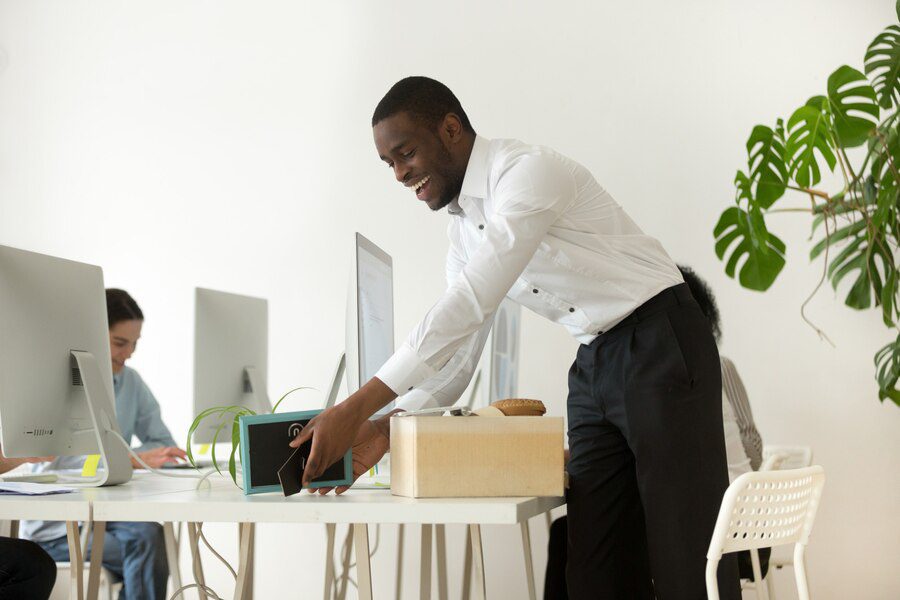 happy african new employee unpacking belongings first working day 1163 5136